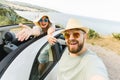 Romantic couple making selfie on smartphone camera in rental cabrio car on ocean or sea beach enjoying summer vacation Royalty Free Stock Photo