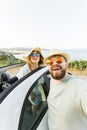 Romantic couple making selfie on smartphone camera in rental cabrio car on ocean or sea beach enjoying summer vacation Royalty Free Stock Photo