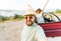 Romantic couple making selfie on smartphone camera in rental cabrio car on ocean or sea beach enjoying summer vacation Royalty Free Stock Photo