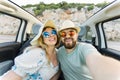 Romantic couple making selfie on smartphone camera in rental cabrio car on ocean or sea beach enjoying summer vacation Royalty Free Stock Photo