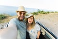 Romantic couple making selfie on smartphone camera in rental cabrio car on ocean or sea beach enjoying summer vacation Royalty Free Stock Photo