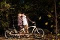 Romantic couple, man and attractive girl close together at tandem bicycle in dark autumn park. Royalty Free Stock Photo