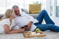 Romantic couple with red wine and food while lying on rug Royalty Free Stock Photo