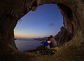 Romantic couple of rock climbers watching sunset from cave in cl Royalty Free Stock Photo