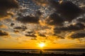 Romantic couple sit down together at the beach enjoying a beautiful coloured sunset with sky and sea in orange - concept of summer Royalty Free Stock Photo