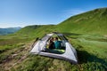 Romantic couple sits in tent overlooking mountain lake amidst scenery mountains