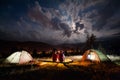 Romantic couple sitting at bonfire near tents in the evening