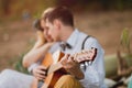 Romantic couple sitting outdoors at sunset with the man playing the guitar Royalty Free Stock Photo