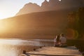 Romantic Couple Sitting On Wooden Jetty By Lake