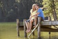 Romantic Couple Sitting On Wooden Jetty Looking Out Over Lake Royalty Free Stock Photo