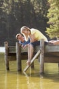 Romantic Couple Sitting On Wooden Jetty Looking Out Over Lake Royalty Free Stock Photo