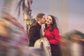 Romantic couple taking a moment to kiss while riding horses on carousel Royalty Free Stock Photo