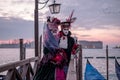 Romantic couple in costume and masks standing with back to the Grand Canal, San Giorgio in the background, during Venice Carnival