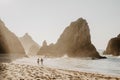 Romantic couple walking along coastline at Ursa Beach among beautiful rocks on sunset. Silhouette Shot. Back view Royalty Free Stock Photo