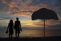 Romantic couple  walking on the beach holding hands together in the  sunset with slippers in hand Royalty Free Stock Photo