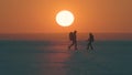 The romantic couple walking through the snow field on sunset background. Royalty Free Stock Photo