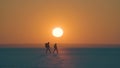 The romantic couple walking through the snow field on sunset background. Royalty Free Stock Photo
