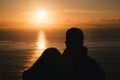Romantic couple watching the sunset in the ocean. Silhouette Royalty Free Stock Photo