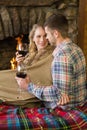 Romantic couple with wineglasses in front of lit fireplace