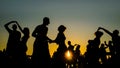 Romantic couples silhouettes dancing against warm sky at sunset