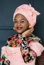 Romantic cute african woman, wearing stylish traditional dress with african print and headwrap, posing on studio dark