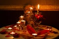 Romantic decoration table set with candles, glasses, roses and Teddy bear, dark warm tone,