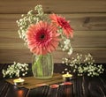 A romantic and delicate bouquet of pink gerberas in a glass vase. Gypsophila flowers, candles, envelopes