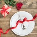 Romantic dinner concept. Festive table setting for Valentines Day on wooden background. Red rose and romantic gift. Top view. Royalty Free Stock Photo
