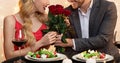 Unrecognizable Man Giving Roses Bouquet To Girlfriend On Date In Restaurant