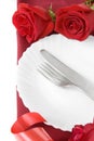 Romantic dinner: plate, cutlery and roses on blue background. served plate with napkin and rose, table setting with roses on plate