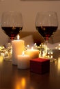 Romantic dinner scene at home: candles, box with a jewel and two glasses of wine. Royalty Free Stock Photo