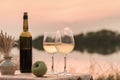 A romantic dinner in summer on a beach at sunset with two glasses of white wine