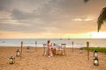 Woman sitting alone on table set with lantern for a romantic meal on beach Royalty Free Stock Photo