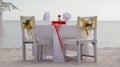 Romantic dinner table set and chair preparation with white theme decoration, white sand, clear cloudy sky, and tranquil, peaceful Royalty Free Stock Photo