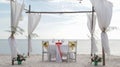 Romantic dinner table set and chair preparation with white theme decoration, white sand, clear cloudy sky, and tranquil, peaceful Royalty Free Stock Photo