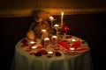 Romantic decoration table set with candles, glasses, roses and Teddy bear. dark warm tone.