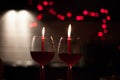 Romantic dinner: two glasses of wine and candels are in the dark with new year lights at the background Royalty Free Stock Photo