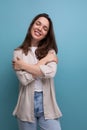 romantic dreaming european young brunette woman in shirt and jeans on blue background