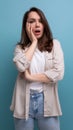 romantic dreaming european young brunette woman in shirt and jeans on blue background