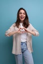 romantic dreaming european young brunette woman in shirt and jeans on blue background