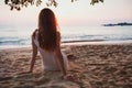beautiful woman sitting alone on calm quiet sunset beach, relaxation