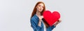 Romantic dreamy cute redhead teenager dreaming about giving boyfriend big red heart card to show her affection and love