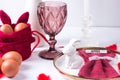 Romantic Easter table setting with candles, white plate, pink wine glass Table decoration with rabbit and painted eggs in red and Royalty Free Stock Photo