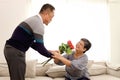 Romantic elderly man gives rose flower bouquet to his wife while sitting in living room, happy smiling Asian senior mature retired Royalty Free Stock Photo