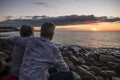 Romantic elderly senior caucasian couple hug and enjoy the sunset at the beach - active mature retired people forever together