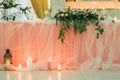 Romantic Elegance: Wedding Table Adorned with Pink Tablecloth, White Tulle, and Glowing Warm Lights and Candles