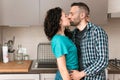 Romantic engaged couple is kissing in the kitchen of their new home - concept of romance and happiness in young couples