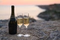 Romantic evening on the background of the sunset. Two glasses of champagne with an open bottle on the edge of a cliff Royalty Free Stock Photo