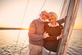 Romantic evening on the boat. Happy senior couple hugging and enjoying amazing sunset while standing on the side of Royalty Free Stock Photo