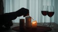 Romantic evening by candlelight. Hands of a man lighting candles with matches close up. Burning candles and glasses with Royalty Free Stock Photo